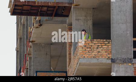 Kiev,Ukraine - 24.04.2019: Le travailleur de la construction sent liquide concrente sur le niveau des joints de brique. Imprimer le ciment. Banque D'Images