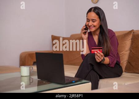 Une jeune femme parle sur un smartphone lors de ses achats en ligne Banque D'Images