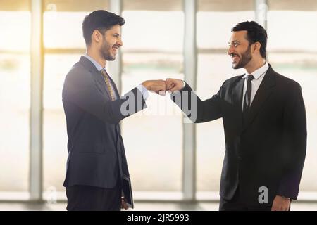 Les employés de l'entreprise qui travaillent dans un cadre professionnel formel se tiennent debout tout en se regardant les uns les autres, souriant. Banque D'Images