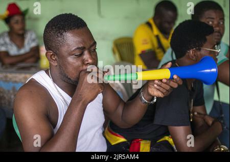 Un fan camerounais souffle un vuvuzela aux couleurs du Gabon dans un restaurant de fortune camerounais dans un quartier populaire de Libreville pendant le match Cameroun-Éthiopie pour la coupe d'Afrique des Nations 2021 au Cameroun sur 14 janvier 2022. Banque D'Images