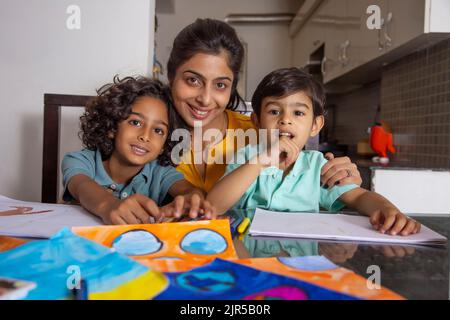 Mère avec ses enfants regardant l'appareil photo pendant la peinture Banque D'Images