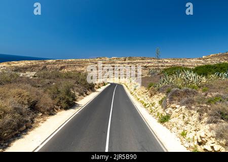 Route déserte à travers un désert et une ville fantôme avec une vue large sur un paysage sur l'île de Gozo à Malte Banque D'Images