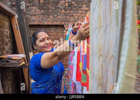 Femme âgée qui pendait des vêtements sur la ligne de lavage pour sécher dans l'arrière-cour Banque D'Images