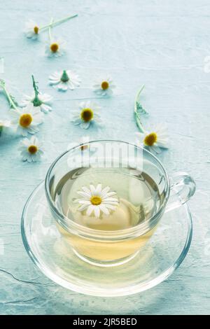 Thé de camomille dans une tasse avec des fleurs volantes, traitement de médecine de fines herbes, avec des fleurs volantes Banque D'Images