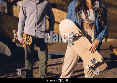 Image de la section médiane de l'homme et de la femme caucasiens avec des planches à roulettes dans le parc de skate Banque D'Images
