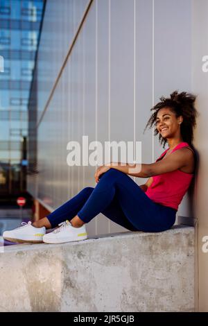 Jeune fille multiraciale dans les vêtements de sport se reposer et s'asseoir après le jogging dans la ville. Banque D'Images