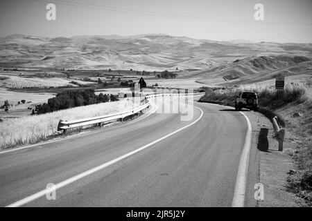 Voyage sur route sinueuse en noir et blanc dans la campagne d'été de l'ouest de la Sicile paysage, Italie Banque D'Images