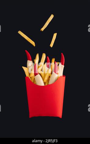 Frites avec ketchup et doigts de sorcière dans une boîte en papier rouge isolée sur fond noir. Halloween horreur concept. Une idée effrayante et effrayante. Banque D'Images
