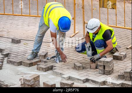Deux briques qui travaillent à la réparation du trottoir dans le district de Port Vell ou du Vieux-Port Banque D'Images