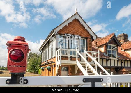 Feu rouge sur les portes de passage à niveau à l'extérieur de la gare royale fermée de Wolferton sur le domaine de Sandringham, Norfolk. Banque D'Images