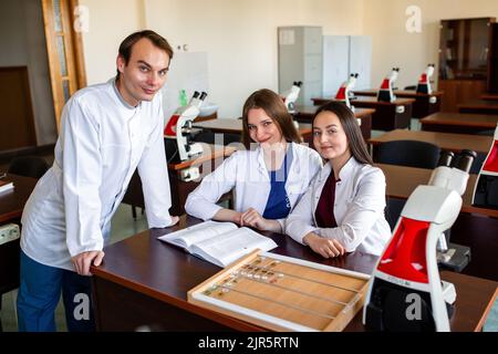 Élèves du secondaire regardant par le microscope en cours de biologie. Jeunes scientifiques faisant des recherches. Banque D'Images