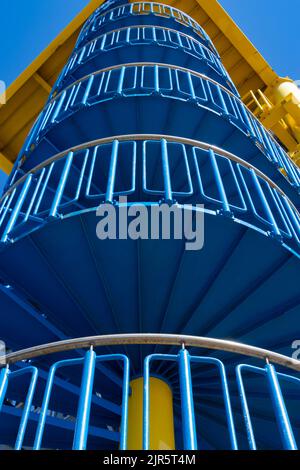 Vue à angle bas d'un escalier en colimaçon bleu avec une plate-forme jaune sur le dessus Banque D'Images