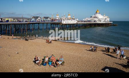 Les gens prennent le soleil d'été en fin d'après-midi sur la plage à côté de Eastbourne Pier, East Sussex, Royaume-Uni. Banque D'Images