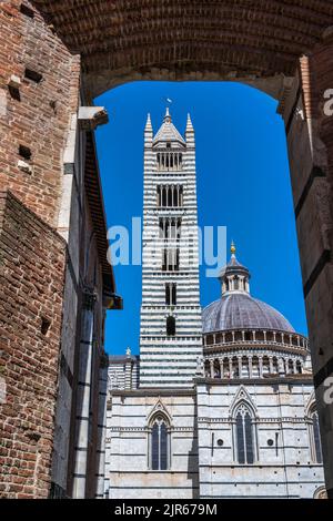 Vue sur le Campanile (clocher) et le Dôme de Sienne (cathédrale de Sienne) à travers l'arche de la via del Castoro à Sienne, Toscane, Italie Banque D'Images