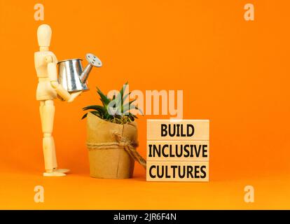 Construire le symbole des cultures inclusives. Les mots-concepts construisent des cultures inclusives sur des blocs de bois. Modèle homme d'affaires. Magnifique arrière-plan orange. Business bui Banque D'Images