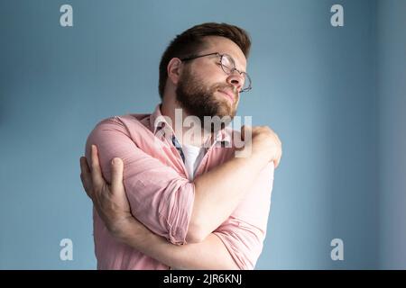 Solitaire, rêvant de l'amour homme en lunettes et une chemise rose se hale doucement, fermant les yeux. Banque D'Images