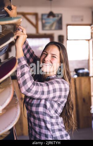 Image verticale de la bonne femme caucasienne posant dans un magasin de skate Banque D'Images