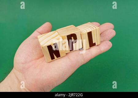 Concept d'entreprise. Sur fond vert, dans les mains d'une personne, cubes avec l'inscription - NPL Banque D'Images