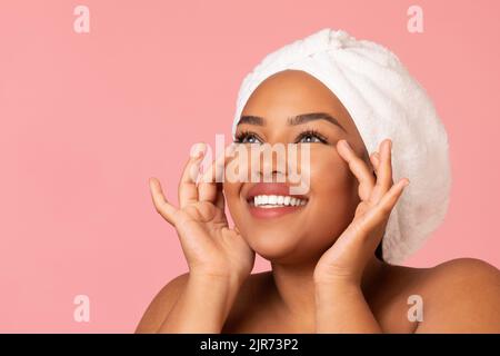 Bonne femme afro-américaine peau hydratante sur fond rose Banque D'Images