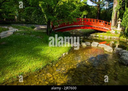 Vue imprenable sur le coucher du soleil sur le pont japonais rouge dans le jardin japonais du musée Albert Kahn - en mai en France (Paris). Les pierres de pas comme chemin de cro Banque D'Images