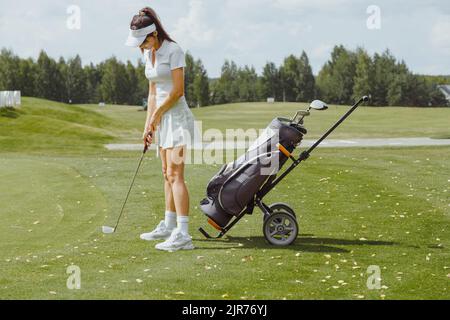 Woman preparing to putt on golf course Banque D'Images