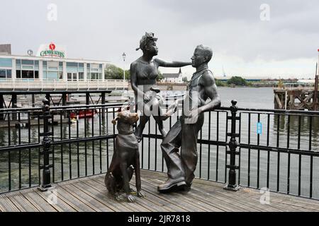 Des gens comme nous - groupe de statue à Cardiff Bay. Été 2022. Baie de Cardiff. Août 2022. Église norvégienne en arrière-plan. Banque D'Images