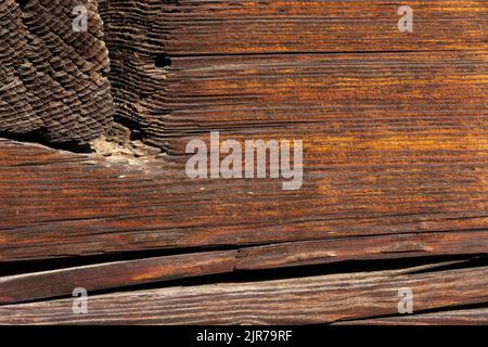 Photo macro d'une ancienne surface de poutre en bois brun foncé abîmée avec texture de grain rugueuse. Banque D'Images