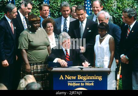 Le président américain Bill Clinton, entouré de membres du Congrès et d'invités, signe la loi sur la réforme du bien-être social lors d'une cérémonie dans le jardin des roses de la Maison Blanche 22 août 1996 à Washington, DC. Les anciens bénéficiaires de l'aide sociale Lillie Harden d'Arkansas, à gauche, Janet Ferrel, de Virginie-Occidentale et Penelope Howard, du Delaware, se trouvent à côté du président. Banque D'Images