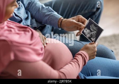 Femmes enceintes islamiques regardant la sonographie de bébé photo tout en étant assis sur le canapé Banque D'Images