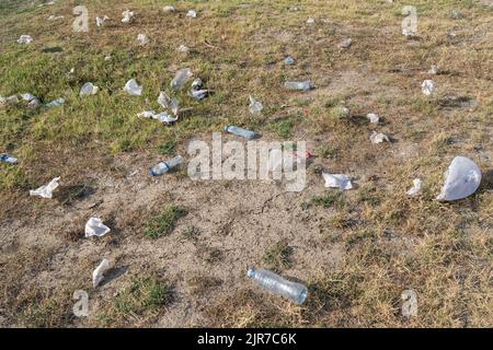 Les bouteilles et les sacs en plastique éparpillés reposent sur l'herbe dans les zones rurales, ce qui entraîne la pollution de l'environnement Banque D'Images