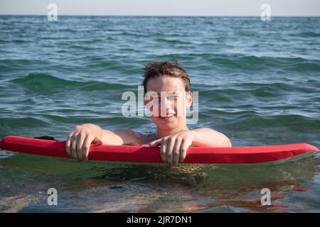 Un garçon adolescent de 17 ans dans la mer avec Une planche de corps Banque D'Images