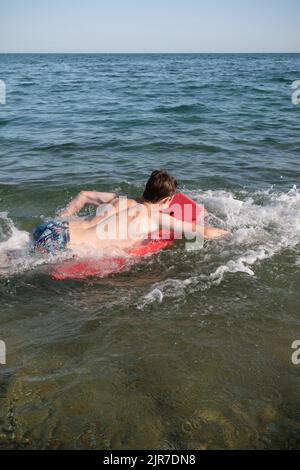 Un garçon adolescent de 17 ans dans la mer avec Une planche de corps Banque D'Images