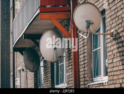 de vieux plats satellites pendent sur le mur d'une vieille maison près des fenêtres Banque D'Images