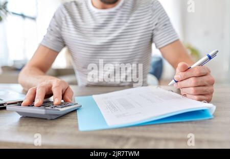 un homme avec des fichiers et une calculatrice travaille au bureau à domicile Banque D'Images
