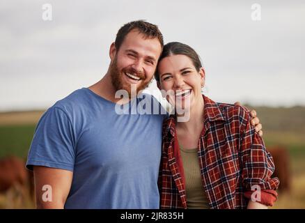 Couple fermier heureux, insouciant et excité debout à l'extérieur sur des terres de bétail ou de bétail. Portrait des amoureux détendus se détendre sur bio ou Banque D'Images