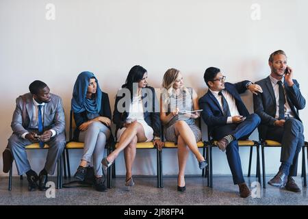 Nous essayons de concentrer Monsieur, un groupe de gens d'affaires confiants qui attendent en file d'attente pour leurs entrevues tandis qu'un homme parle fort sur son téléphone portable Banque D'Images