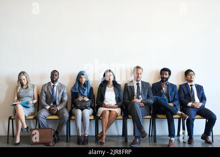 Seul le meilleur sera le faire : un groupe de gens d'affaires bien habillés assis dans la file d'attente d'être interviewés. Banque D'Images