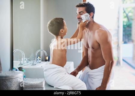 Il est malade du mettre pour vous. Un beau jeune homme qui apprend à son fils comment se raser dans la salle de bains. Banque D'Images