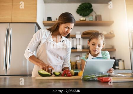 Quelle est la prochaine étape, cher. Une mère et sa jeune fille essayant ensemble une nouvelle recette dans la cuisine. Banque D'Images