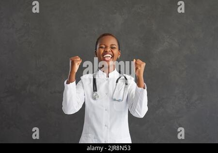 La jeune femme afro-américaine se réjouit sincèrement de soulever des poings et de sourire. Banque D'Images
