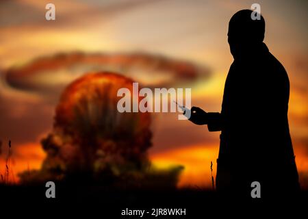 Le concept d'une frappe nucléaire. Silhouette d'un homme avec une télécommande dans ses mains faisant une explosion. Un homme politique qui a lancé une guerre nucléaire Banque D'Images