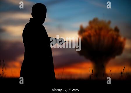 Le concept d'une frappe nucléaire. Silhouette d'un homme avec une télécommande dans ses mains faisant une explosion. Un homme politique qui a lancé une guerre nucléaire Banque D'Images