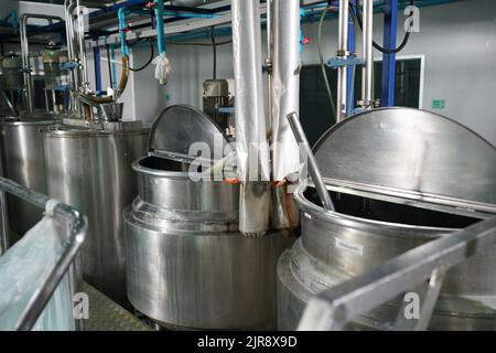 Vue de l'intérieur de l'usine de boissons non alcoolisées et réservées. Travailleur contrôlant le travail de la machine dans la chaîne de production de l'industrie des boissons. Banque D'Images