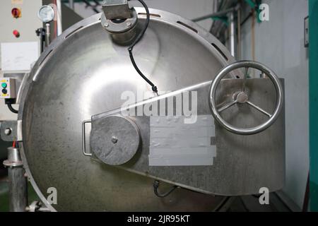 Vue de l'intérieur de l'usine de boissons non alcoolisées et réservées. Travailleur contrôlant le travail de la machine dans la chaîne de production de l'industrie des boissons. Banque D'Images