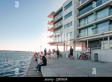 Oslo; Norvège - 13 août 2022: Les personnes fortuites apprécient le coucher de soleil sur le front de mer de Tjuvholmen. Banque D'Images