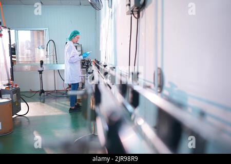 Travailleurs asiatiques travaillant dans l'industrie alimentaire et des boissons pour l'usine de l'industrie des boissons avec travail d'hygiène personnel d'inspecteur de ligne de production de jus de fruits. Inspecter le faisceau Banque D'Images