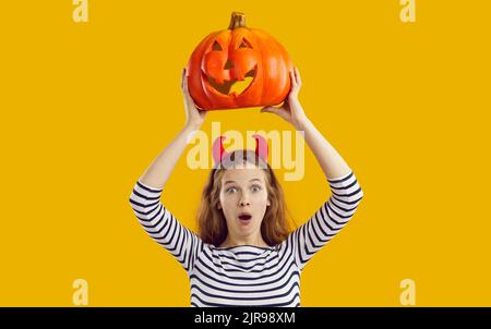 Portrait de studio de femme avec drôle d'expression de visage surpris tenant la citrouille d'Halloween Banque D'Images