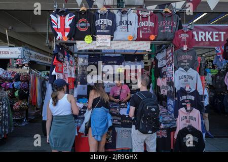 Les touristes achetant des T-shirts au marché Covent Garden à Londres en été Banque D'Images