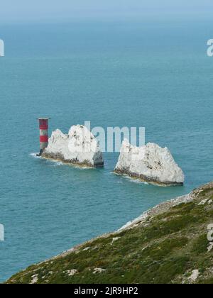 Le phare au niveau des aiguilles dans une mer acidiée et derrière des affleurements déchiquetés, ressemblant à des dents qui s'étendent de la falaise, qui montrent clairement pourquoi la balise est nécessaire Banque D'Images