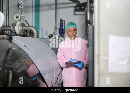 Travailleurs asiatiques travaillant dans l'industrie alimentaire et des boissons pour l'usine de l'industrie des boissons avec travail d'hygiène personnel d'inspecteur de ligne de production de jus de fruits. Inspecter le faisceau Banque D'Images